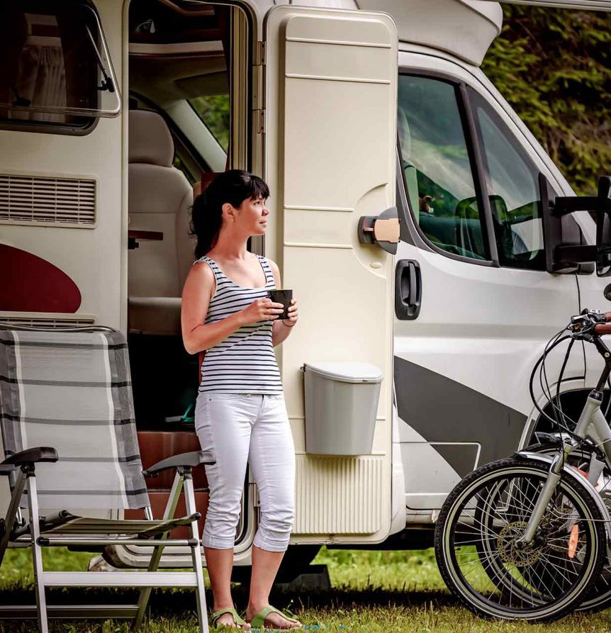 woman standing outside with a cup of coffee in front of RV